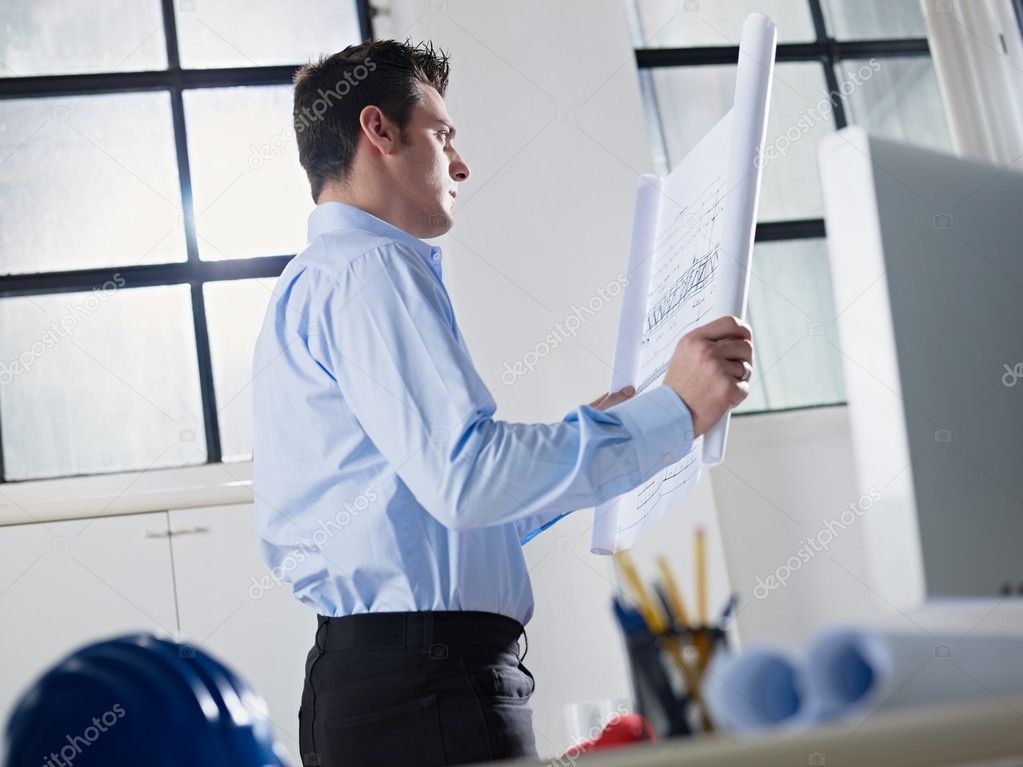 Architect reading blueprint in office