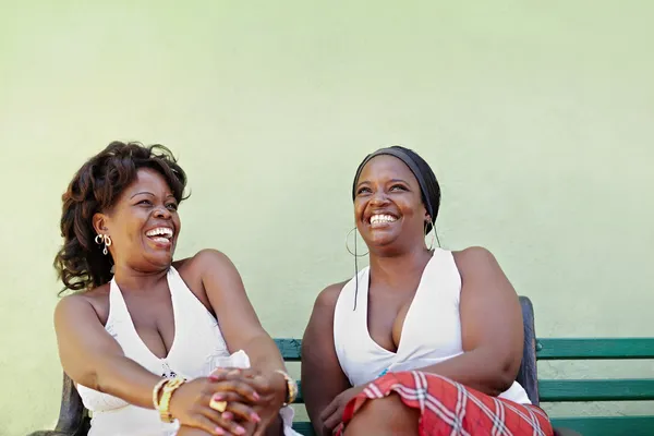 Siyah kadınlarla beyaz elbise bankta gülüyor — Stok fotoğraf
