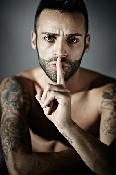 Hombre tatuado con el dedo en la boca — Foto de Stock