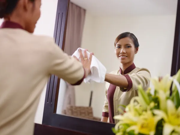 Asiática criada trabajando en hotel habitación y sonriendo —  Fotos de Stock