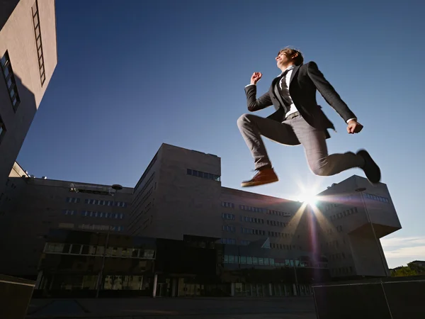 Geschäftsmann springt und lächelt vor dem Büro — Stockfoto
