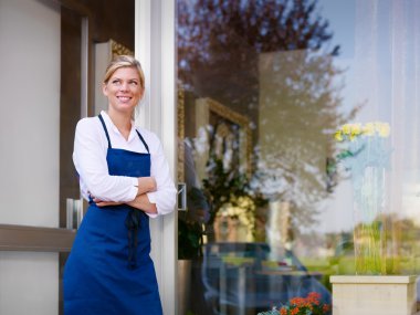 Young pretty woman working as florist in shop and smiling clipart