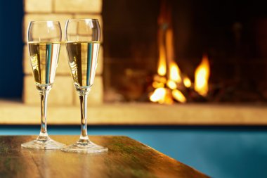 Two flutes filled with champagne near fireplace clipart