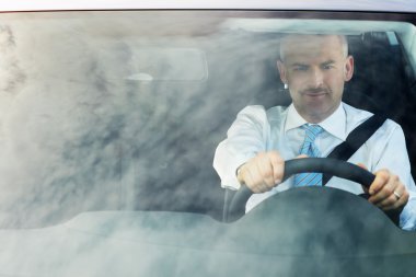 Businessman driving car with sky reflections on windshield clipart