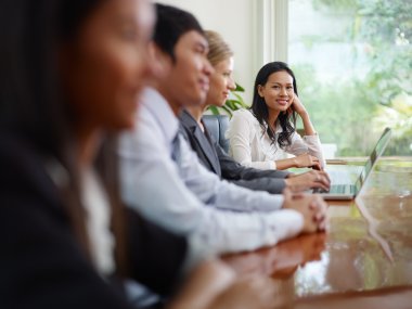 Businesspeople talking in meeting room and woman smiling clipart