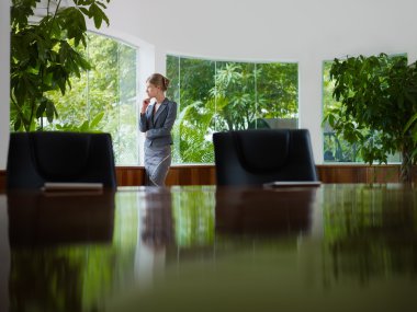 Businesswoman contemplating out of window in meeting room clipart