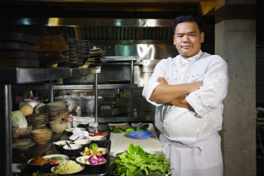 Asian chef smiling at camera in restaurant kitchen clipart