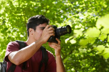 Young male photographer hiking in forest clipart