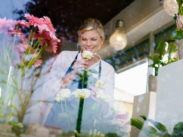 Chica rubia trabajando en floristería con rosas y gerberas — Foto de Stock