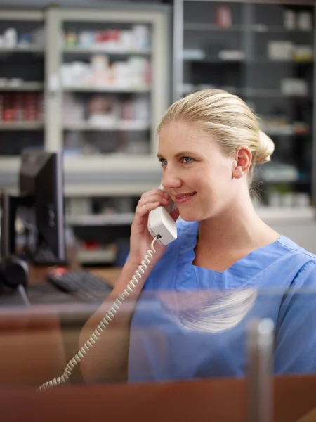 Женщина работает медсестрой в клинике и говорит по телефону — стоковое фото