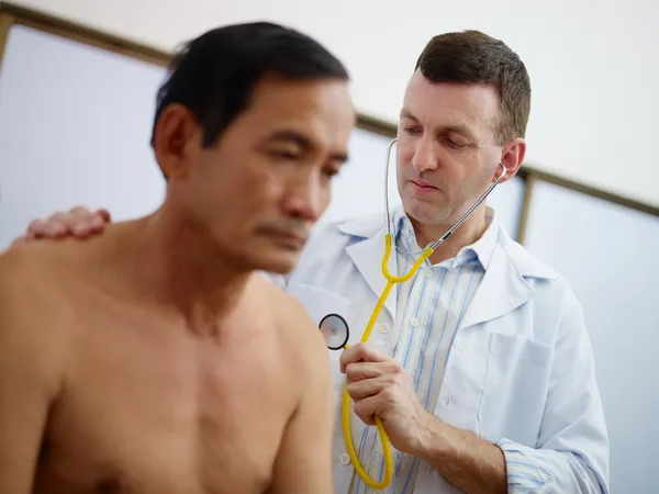 Médecin travaillant et visitant vieil homme à la clinique — Photo