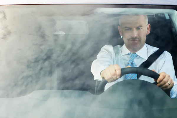 Uomo d'affari guida auto con riflessi del cielo sul parabrezza — Foto Stock