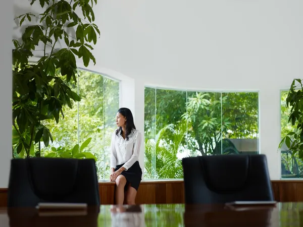 Бізнес-леді розмірковує з вікна в кімнаті для переговорів — стокове фото