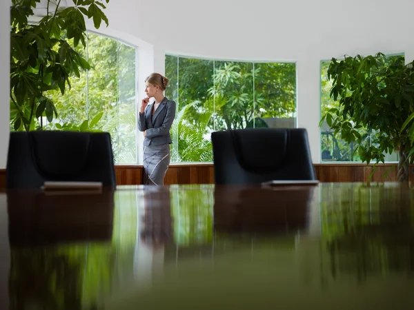 Mujer de negocios contemplando por la ventana en la sala de reuniones —  Fotos de Stock