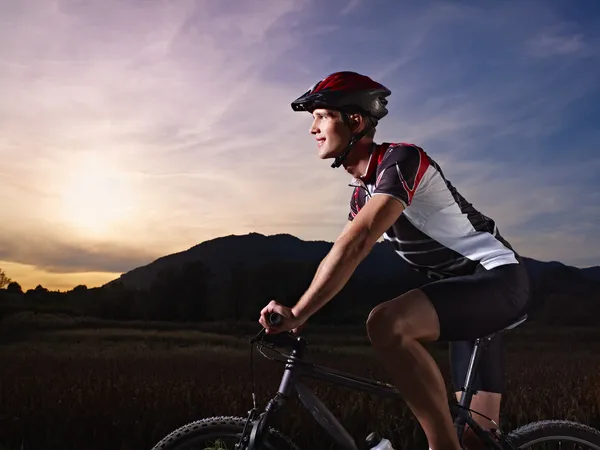 Ung man utbildning på mountainbike i solnedgången — Stockfoto