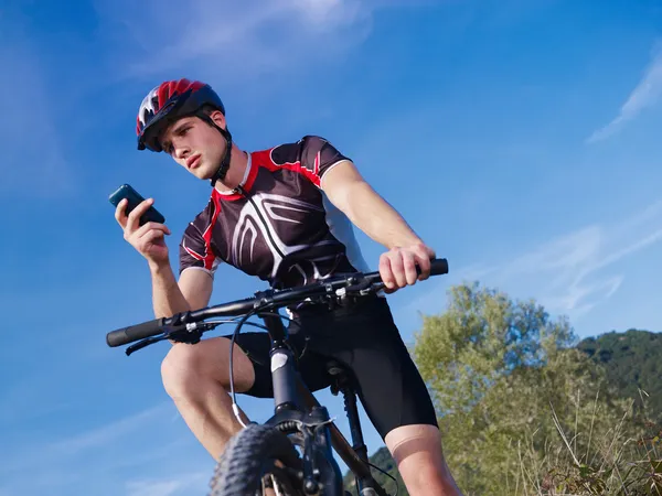 Joven con teléfono a caballo bicicleta de montaña — Foto de Stock