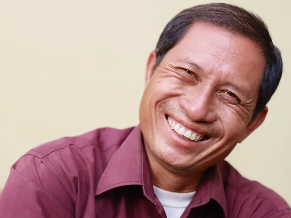 Счастливый зрелый азиат улыбается и смотрит в камеру — стоковое фото