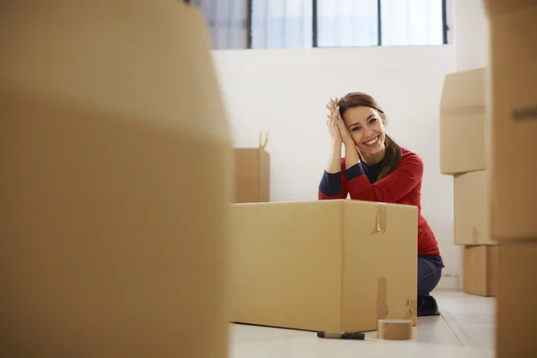 Счастливая женщина улыбается дома во время переезда с коробками — стоковое фото