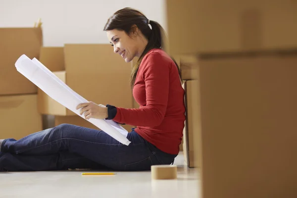 Женщина читает планы нового дома во время переезда — стоковое фото