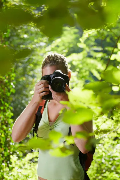 Ung kvinnlig fotograf vandring i skogen — Stockfoto