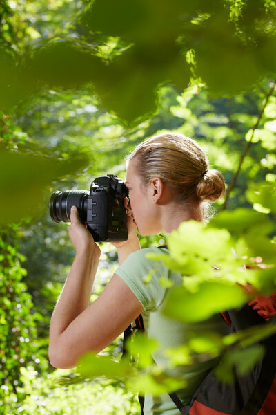 Young female photographer hiking in forest