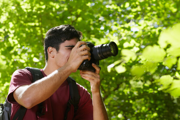Young male photographer hiking in forest