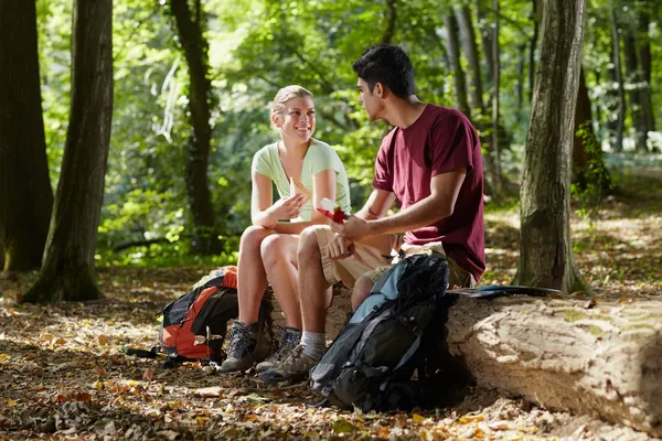 Paret sitter på stammen och äta mellanmål efter trekking — Stockfoto