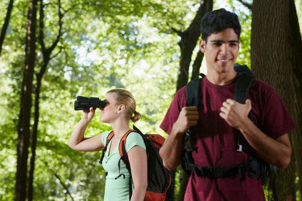 若い男性と女性の双眼鏡で森でのハイキング — ストック写真