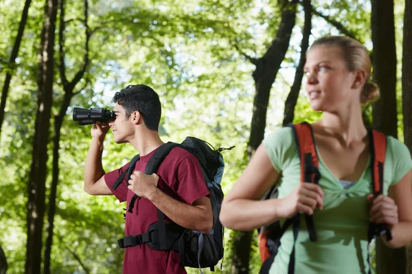 Jonge man en vrouw wandelen in het bos met een verrekijker — Stockfoto