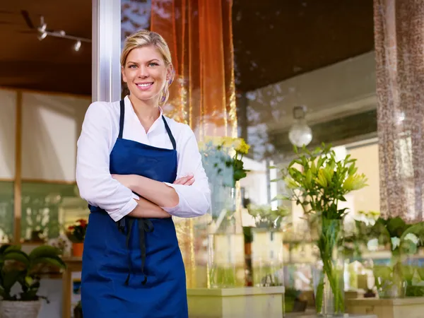 Young pretty woman working as florist in shop and smiling — Stockfoto