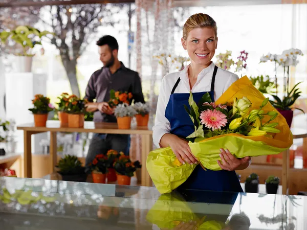 Mladá žena a klient v prodejně květiny — Stock fotografie
