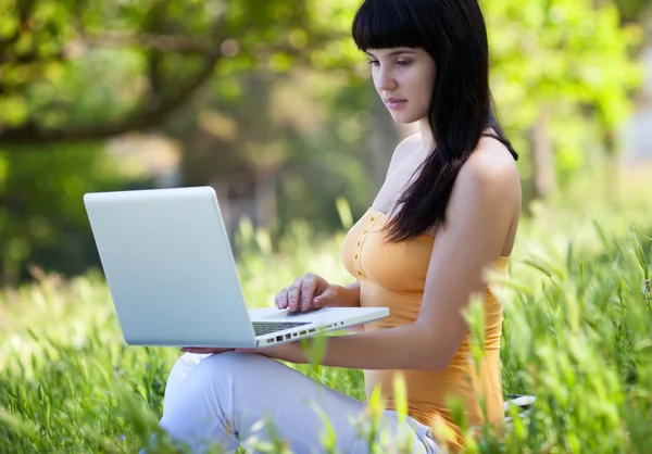 Девушка с ноутбуком в парке — стоковое фото