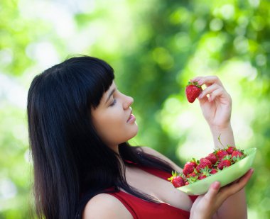 Girl with straberry in garden clipart