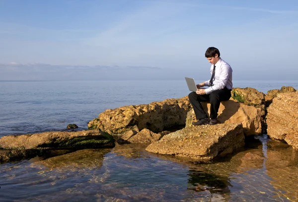 Бизнесмен, работающий с ноутбуком на берегу моря — стоковое фото