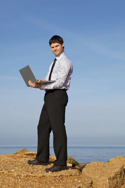 Человек у моря с ноутбуком — стоковое фото