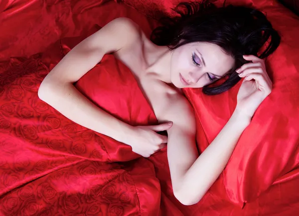 Girl sleeping on red silk — Stock Photo, Image