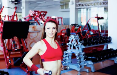 Girl with dumbbell in fitness center clipart