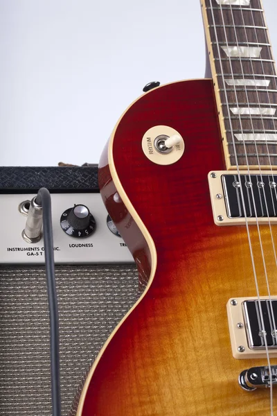 Guitarra eléctrica Sunburst apoyada en un amplificador vintage con cable de conexión —  Fotos de Stock