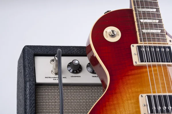 Sunburst guitarra elétrica apoiada em um amplificador vintage com cabo de remendo — Fotografia de Stock