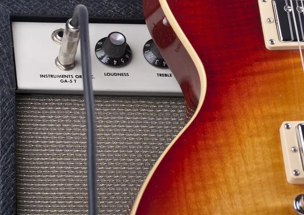 Guitarra eléctrica Sunburst apoyada en un amplificador vintage con cable de conexión —  Fotos de Stock