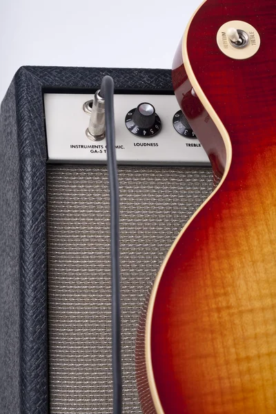 Guitarra eléctrica Sunburst apoyada en un amplificador vintage con cable de conexión —  Fotos de Stock