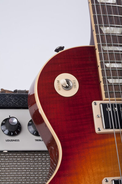 Beautiful sunburst electric guitar leaning against a vintage amplifier with knobs showing