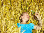 Szép, mosolygós lány veszi napozni arany mezőben