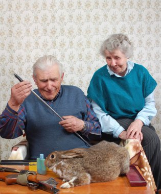 Grandparent and rabbit prepare double-barrelled gun to hunt clipart