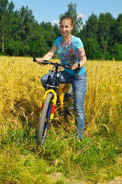 Hermosa chica sonriente en bicicleta cerca del campo —  Fotos de Stock