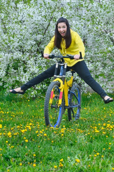 Mujer joven sobre hierba verde con bicicleta —  Fotos de Stock
