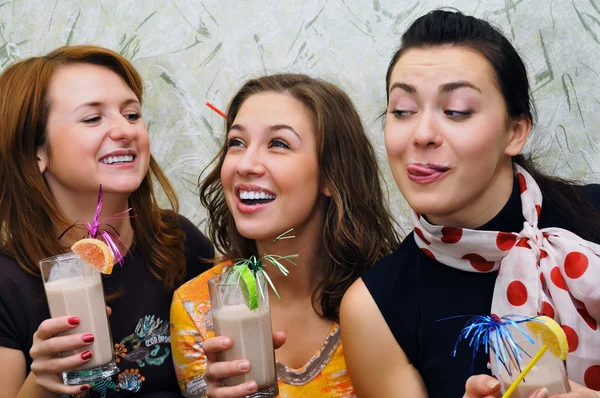 Tre vackra glada unga flickor dricka drinkar med frukter — Stockfoto