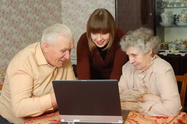 Бабушка с дедушкой и внучкой смотрят на ноутбук — стоковое фото