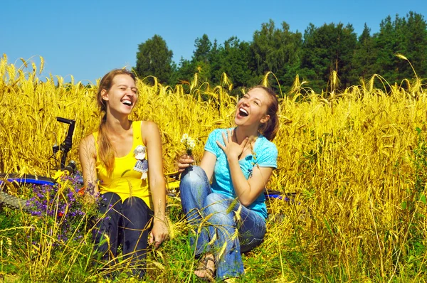 Two laughing pretty girls rest in golden field — Stock Photo, Image