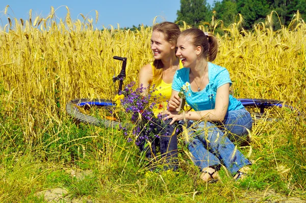 Duas garotas bonitas rindo descansam no campo dourado — Fotografia de Stock